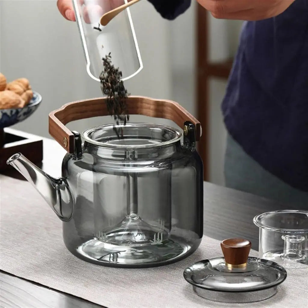 Close-up of premium borosilicate glass teapot showcasing natural ashwood handle and integrated tea infuser