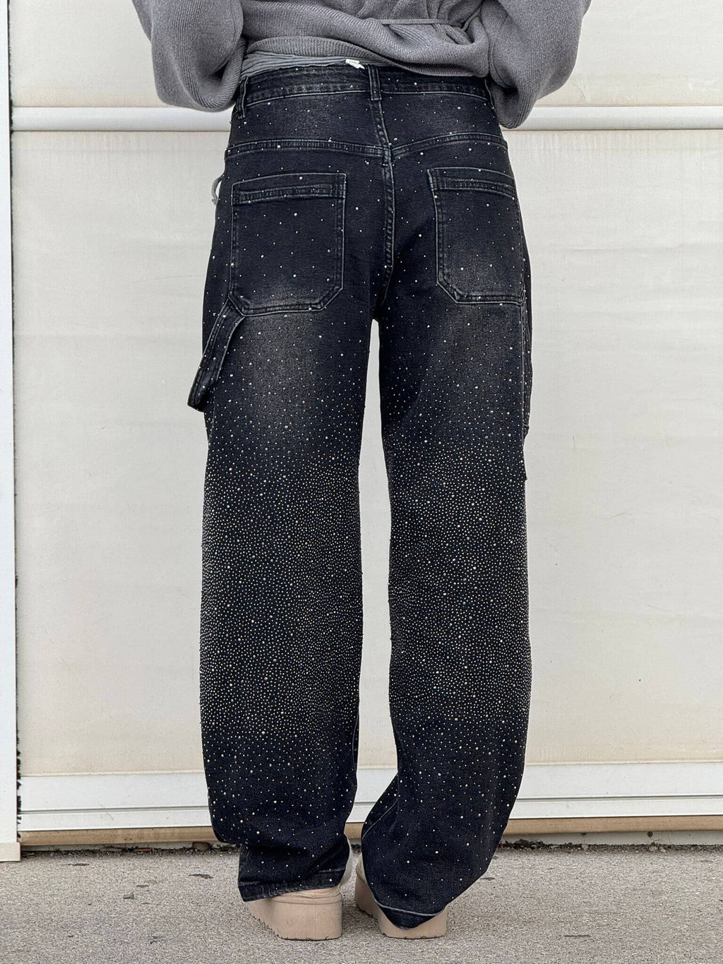 Jeans neri da uomo con effetto spruzzato bianco, tasche posteriori, vestibilità ampia. Stile casual, moda streetwear.