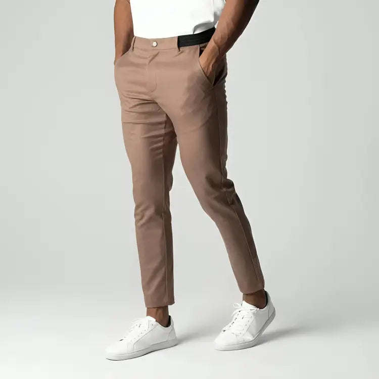 Pantaloni chino beige da uomo, vestibilità slim, tasche laterali, abbinati a scarpe bianche e maglietta bianca. Moda casual elegante.
