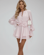 Model wearing Lauven Florence Mini Dress in soft pink with 3D embellishments and flare sleeves.
